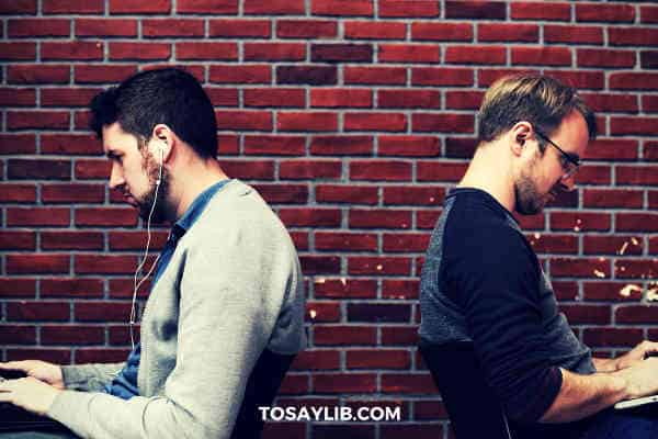 two men siting back to back typing on computers