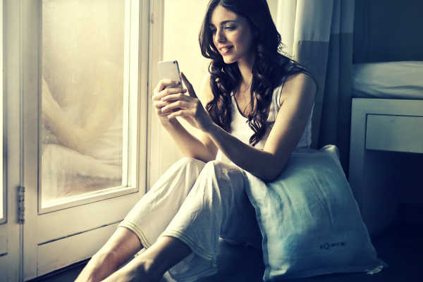 pretty girl looking at phone in bedroom