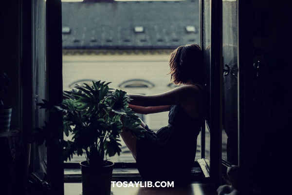 girl being sad sitting next to window