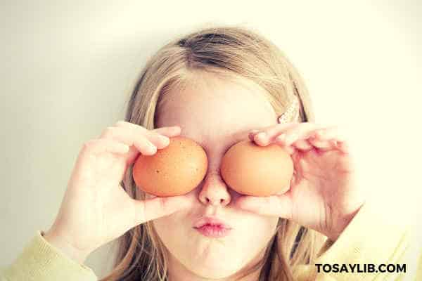 little girl holding eggs on her eyes