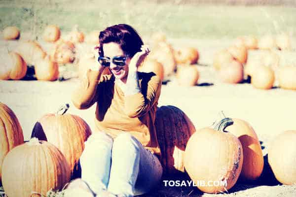 lady sitting among pumkins