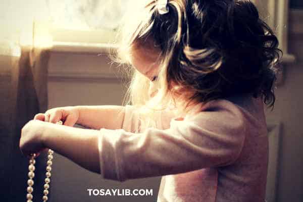 little girl holding a necklace of pearl