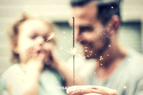 dad holding daugther playing firework