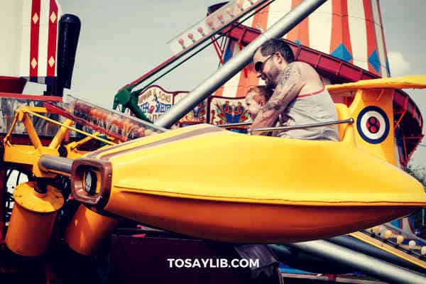 dad playing with son on a game machine in a theme park