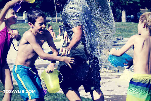 dad playing with kids pouring water