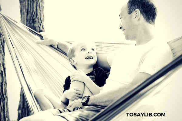 dad sitting on hammock with son