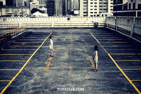 women stand still empty parking lot