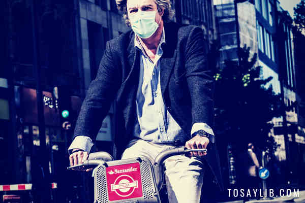 man wearing mask riding bicycle