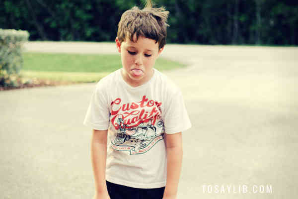 little boy tongue out in a park feeling upset