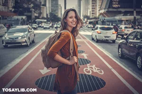 16 Happy girl with backpack in the middle of a street looking back