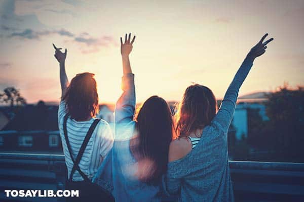 28 Three female friends raising their hands to the sky