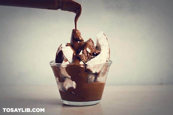 64 chocolate being poured on creamy dessert