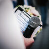 08-Featured-Photo-of-a-person-holding-a-microphone-while-holding-a-clipboard-and-a-boquet-of-flowers