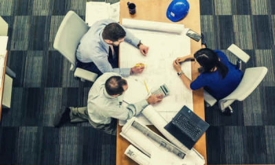 04-feature-three-people-sitting-beside-table-working-on-architect-blueprint-business