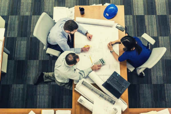 04-feature-three-people-sitting-beside-table-working-on-architect-blueprint-business