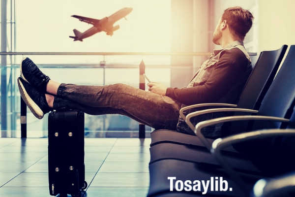 man casual clothes sitting luggage bag airplane sky