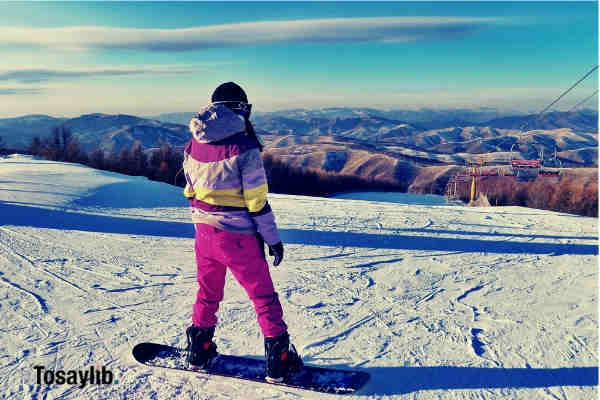 person snowboarding on field pink snow suit snow sky mountains