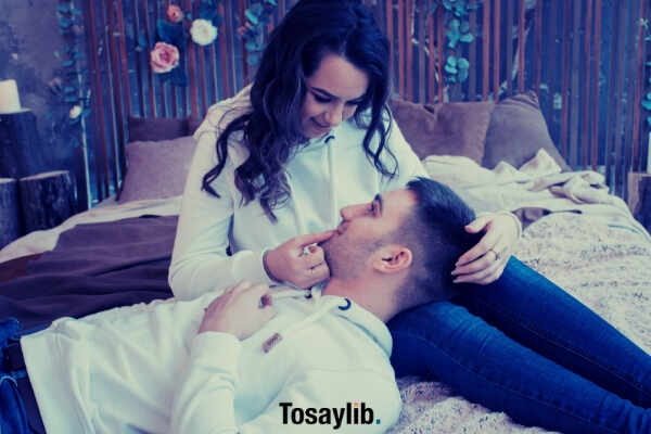 man-and-woman-white-sweater-guy-lying-on-bed-woman-sitting-looking-on-each-other