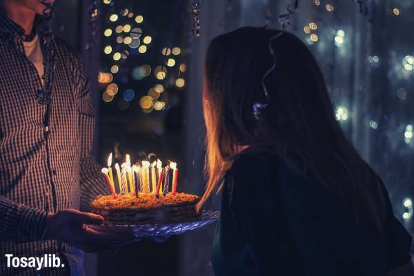 man holding birthday cake woman blowing candle