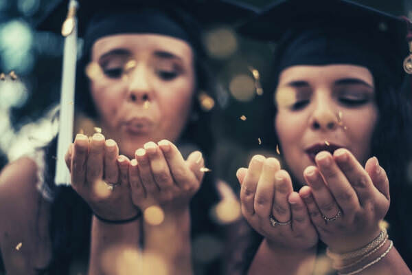 01-feature-two-women-wearing-graduation-hat-blowing-confetti