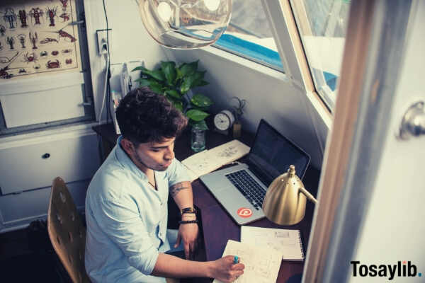 man working laptop beside window