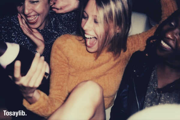 three smiling woman holding wine