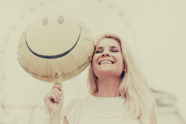 feature-woman-holding-a-smiley-balloon