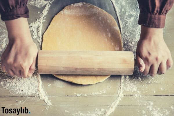 person flattening dough with rolling pin