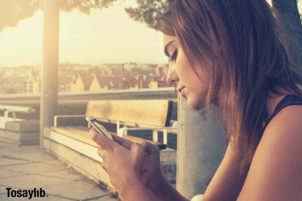 woman with black dress using a smartphone