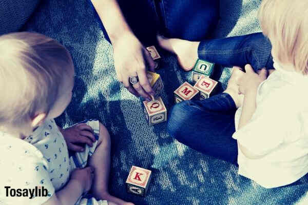 person teaching two kids letters blocks
