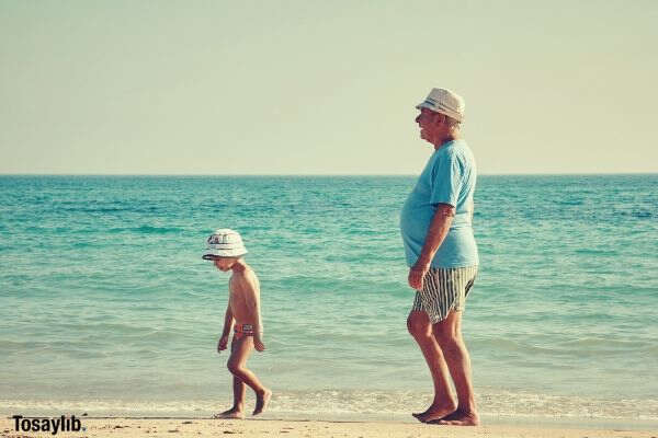 boy and grandpa walking on beach side