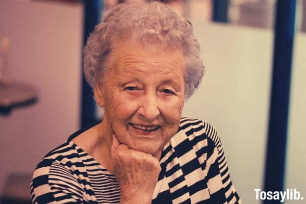 smiling woman wearing black and white top resting head on right hand