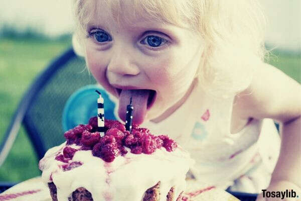 toddler licking her birthday cake