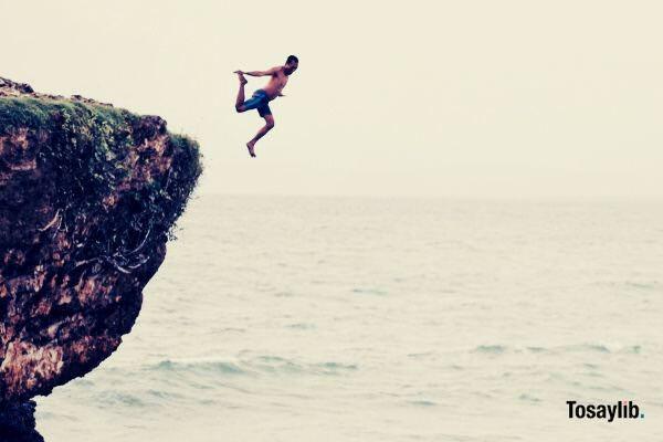 man jumping on cliff ocean