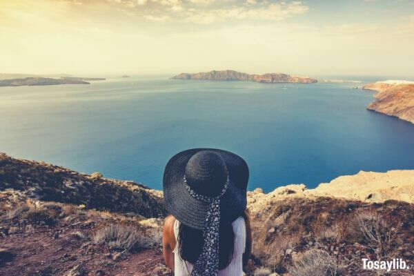woman wearing hat facing lake