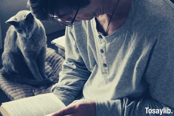 the man reads the book of the house together with a cat and it is pleasant to a cat