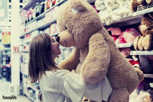 woman carrying bear plush toy inside store