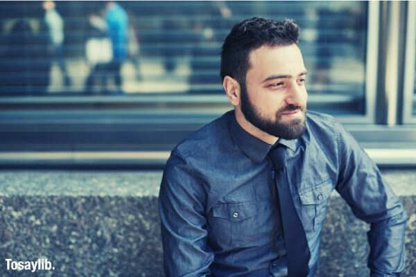 young bearded brazilian man relaxes on a bench in the financial district in new york city