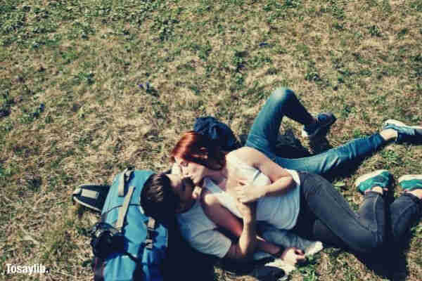 couple lying on grass bag kissing