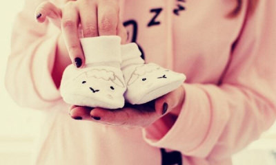 woman-holding-baby-s-pair-of-white-shoes