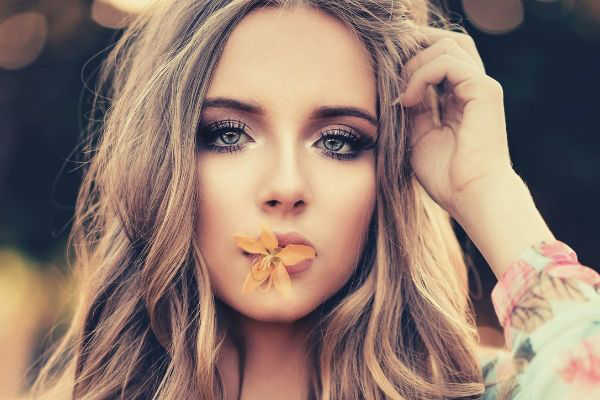 feature-woman-with-orange-petaled-flower-on-her-lips