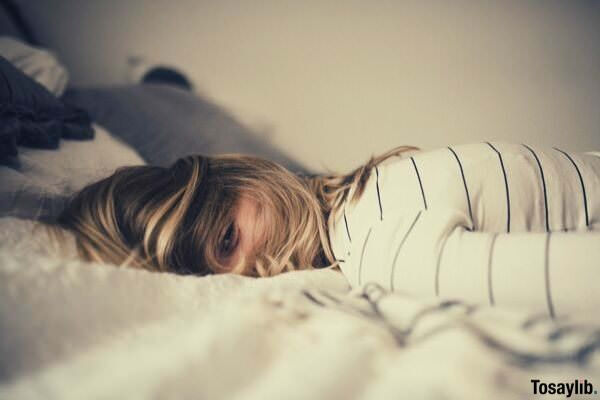 blonde haired Girl lying on the white bed