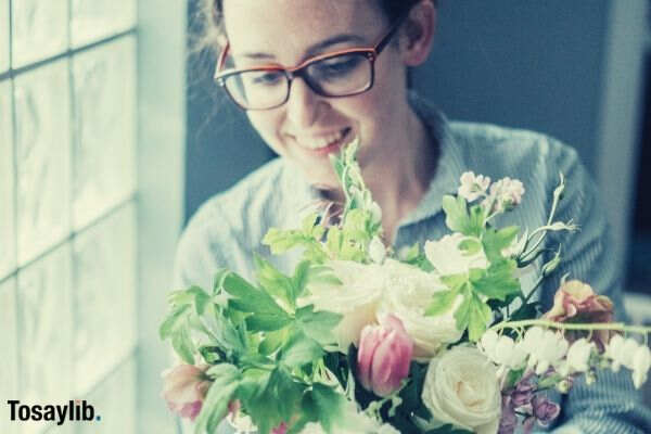 woman makes a flower bouquet by a window in natural light
