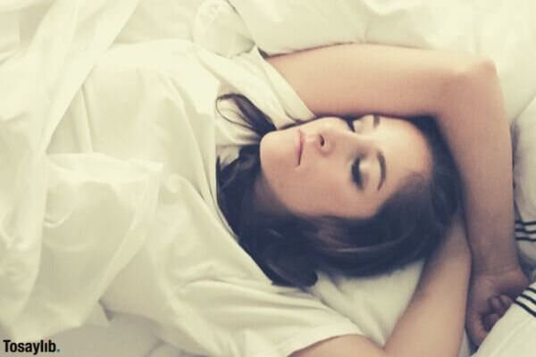 young woman sleeping in bed with white sheets