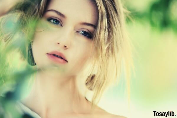 close up photo of a woman behind leaves