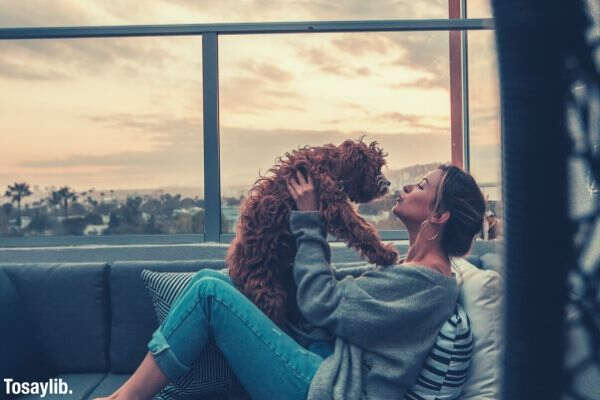 woman holding dog while sitting on the sofa