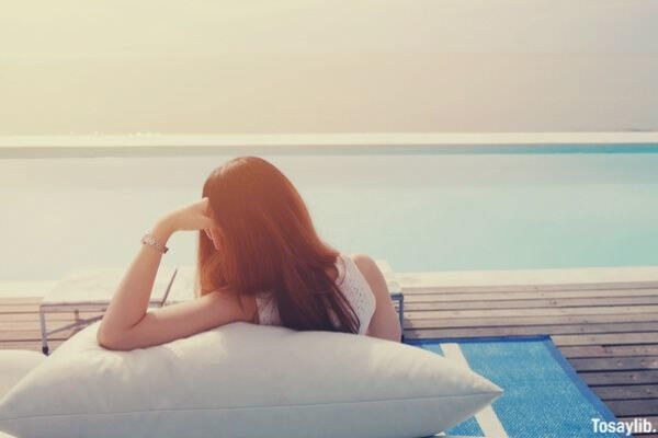 woman feeling relax on bean bag nearby the swimming pool at the luxury resort