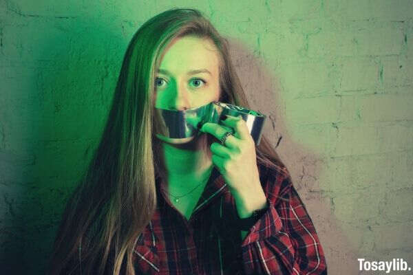 woman placing duct tape on her mouth