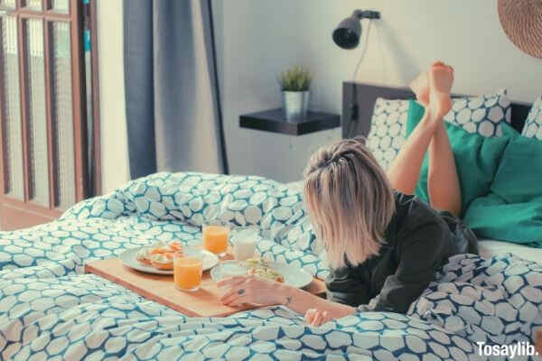 woman lying on bed food board