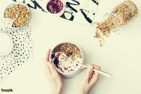 person mixing cereal milk and strawberry jam on white ceramic bowl